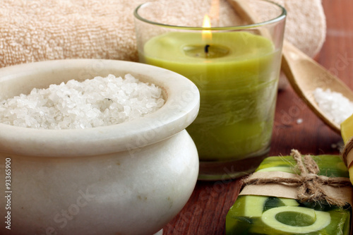 the soap and towel next to sea salt and candle on wooden background