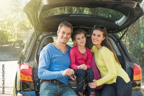family sitting in the trunk of their car on a country road