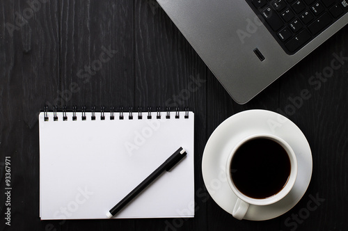 Laptop  cup of coffee and notebook on dark table