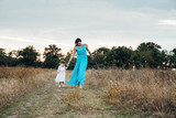 mother and daughter playing on autumn field together, loving family having fun outdoors