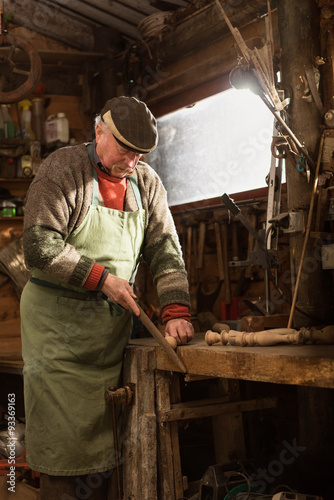 A grandfather is working on a wooden leg in his workshop.