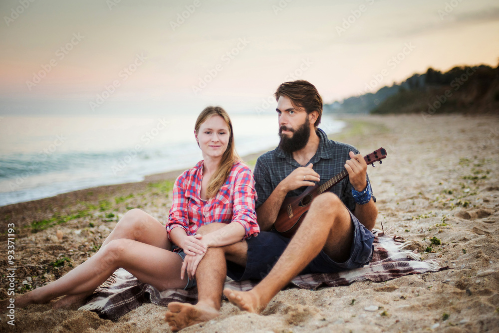 Obraz premium caucasian couple on seaside playing ukulele 