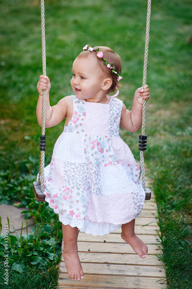 Adorable baby girl enjoying a swing ride on a playground in a park Adorable baby girl enjoying a swing ride on a playground in a park