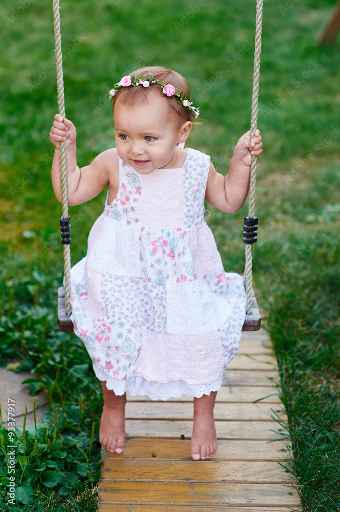 Adorable baby girl enjoying a swing ride on a playground in a park Adorable baby girl enjoying a swing ride on a playground in a park