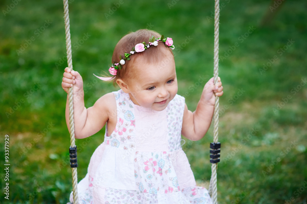 Adorable baby girl enjoying a swing ride on a playground in a park Adorable baby girl enjoying a swing ride on a playground in a park