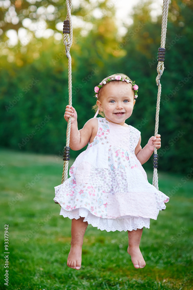 Adorable baby girl enjoying a swing ride on a playground in a park