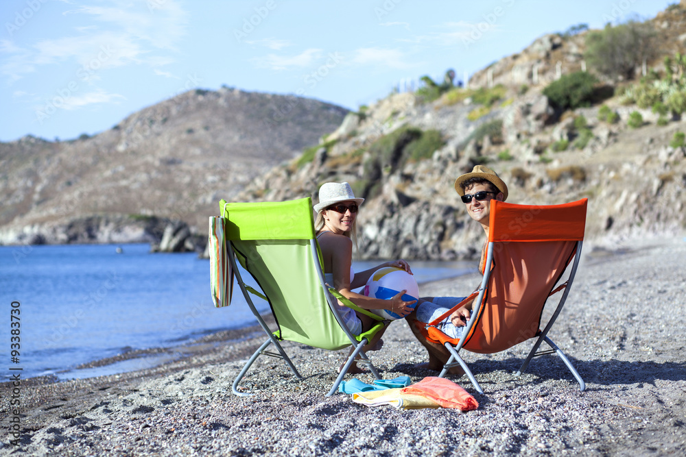 Young couple is sitting on chaise lounge at the beach Young couple is sitting on chaise lounge at the beach
