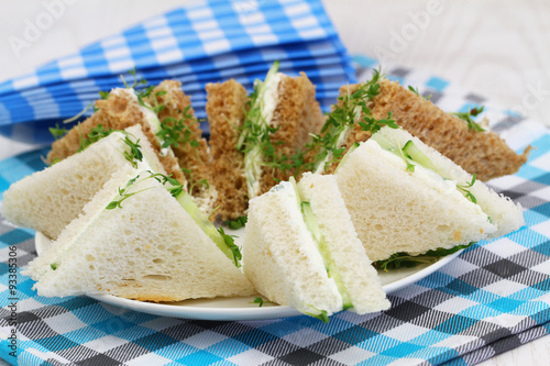 Traditional white and brown cream cheese and cucumber sandwiches and checkered napkins 