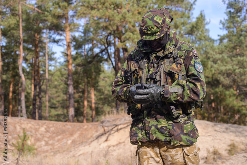 Man in military uniform with portable radio in forest