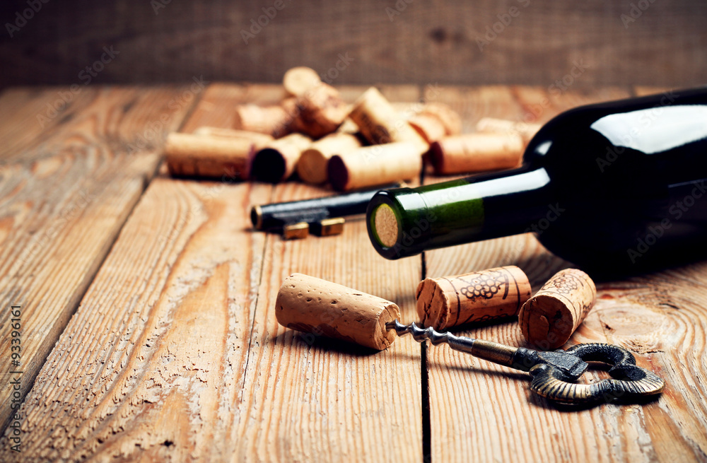 Wine corks, bottle and corkscrew on a wooden table