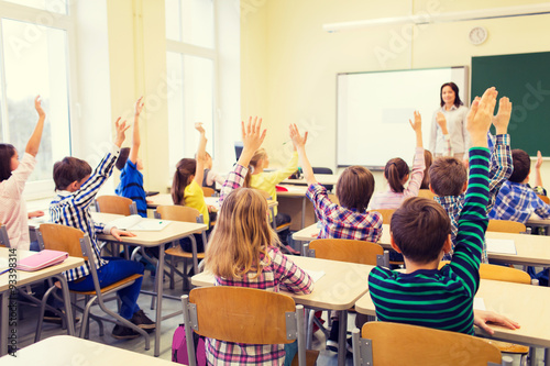 Canvas Print group of school kids raising hands in classroom