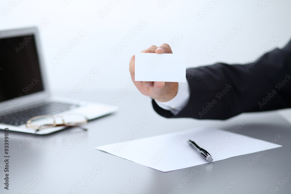 Close-up of businessman giving a business card, sitting at the table Close-up of businessman giving a business card, sitting at the table