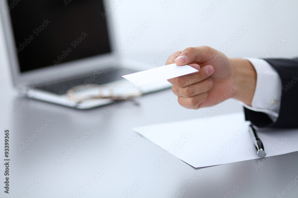 Close-up of businessman giving a business card, sitting at the table Close-up of businessman giving a business card, sitting at the table