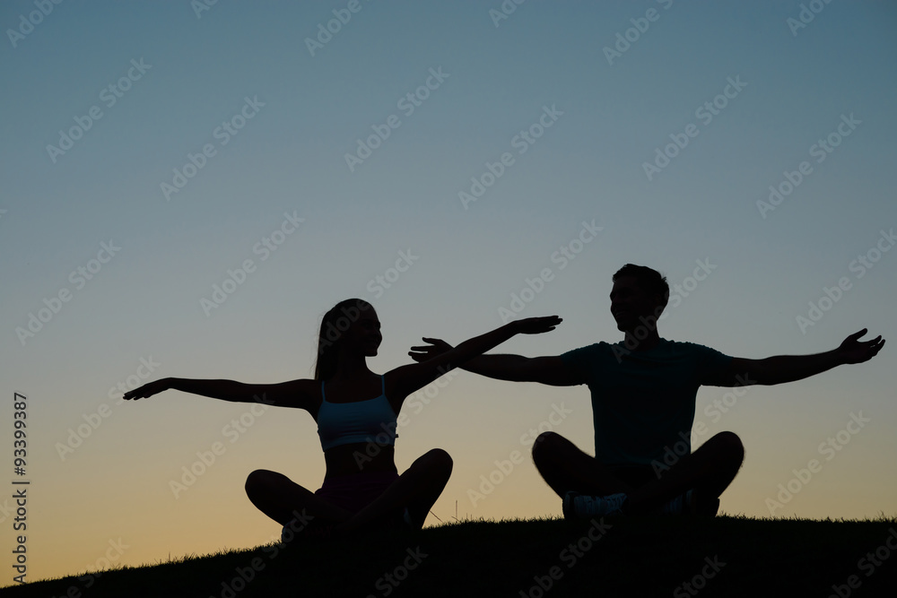 Boy and girl waving their hands at sunset.