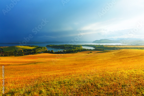 Beautiful landscape, yellow meadow and lake with mountains 