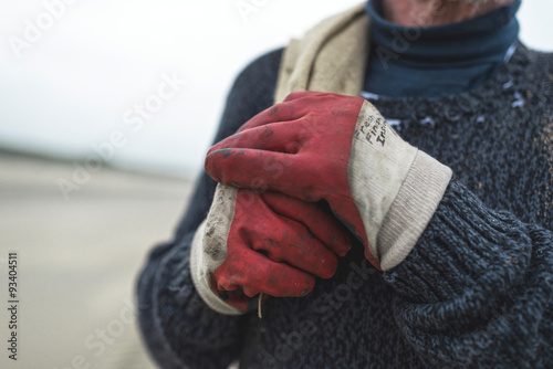 Close-up of work gloves from beachcomber holding burlap sack. photo
