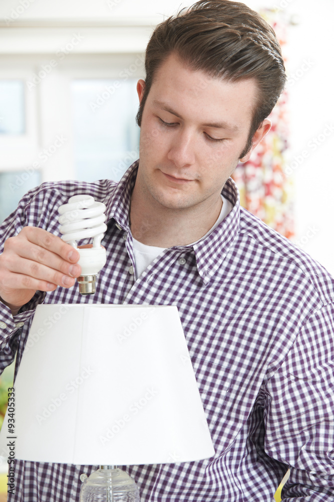 Man Putting Low Energy Lightbulb Into Lamp At Home Man Putting Low Energy Lightbulb Into Lamp At Home