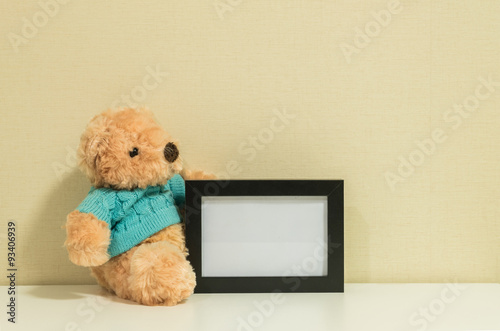 Frame for a photo with brown bear doll on wall room background