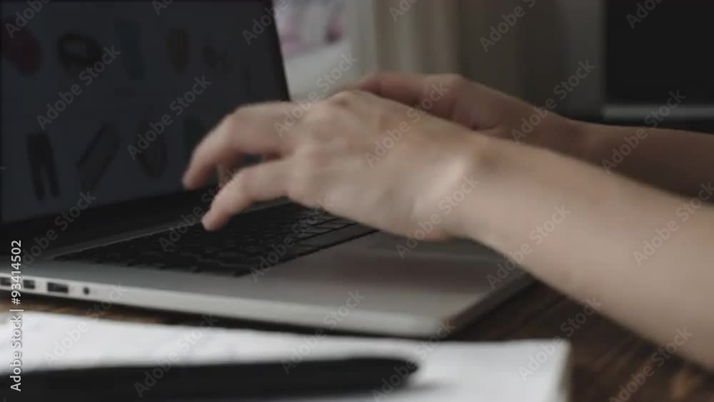 Woman working with laptop placed on wooden desk Woman working with laptop placed on wooden desk