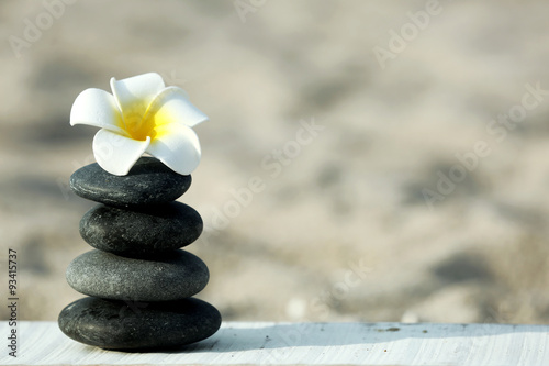 Spa stones with flower on sand beach close up