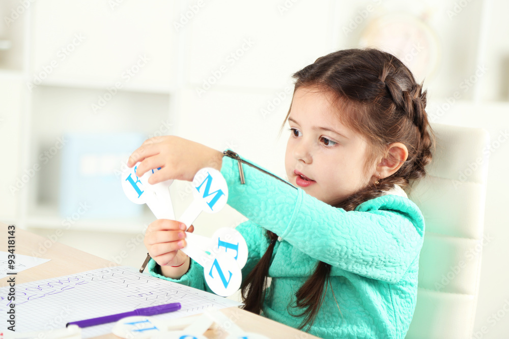 Cute little girl doing her homework, close-up, on home interior background Cute little girl doing her homework, close-up, on home interior background