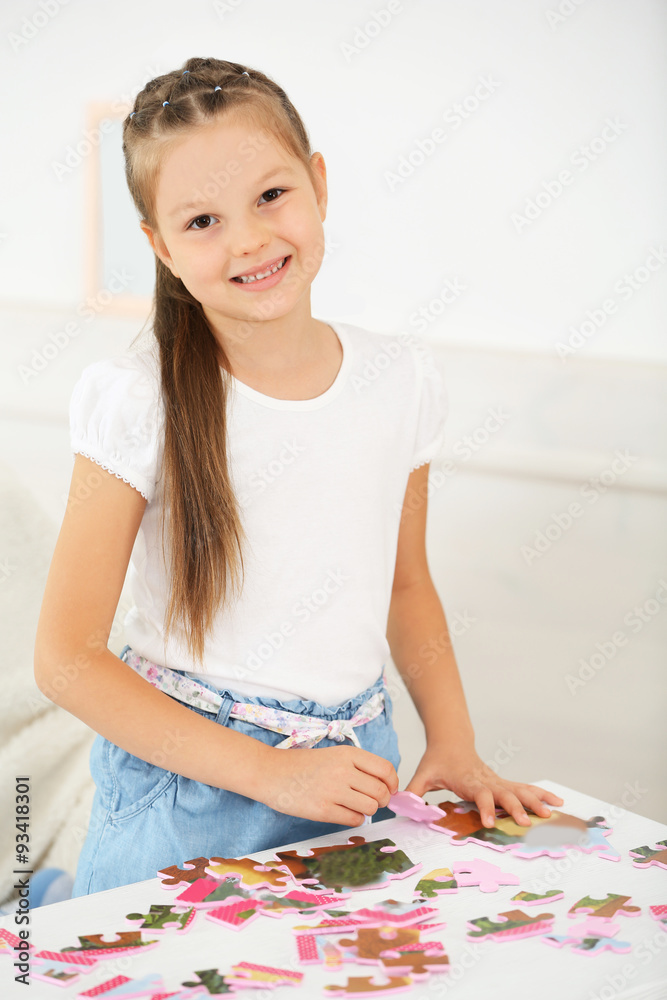Cute little girl playing with puzzles on home interior background Cute little girl playing with puzzles on home interior background