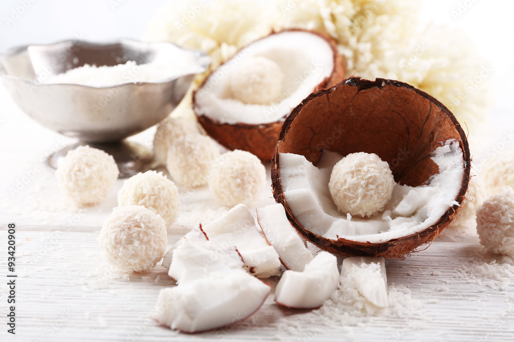 Candies in coconut flakes and fresh coconut on light wooden background Candies in coconut flakes and fresh coconut on light wooden background