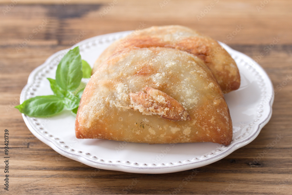 pie with meat with basil on white plate on brown wooden background