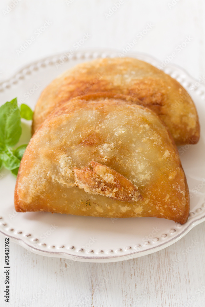 pie with meat with basil on white plate on white wooden background