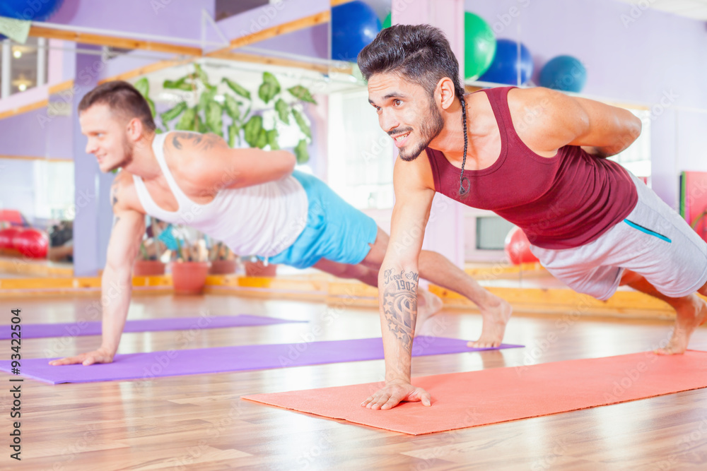 Two young multiracial men doing pushups indoor