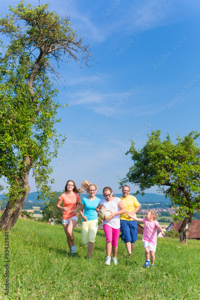 Fototapeta premium Father with children running on green meadow grass