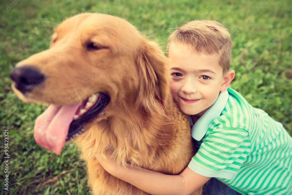 Cute little boy hugging his golden retriever pet dog