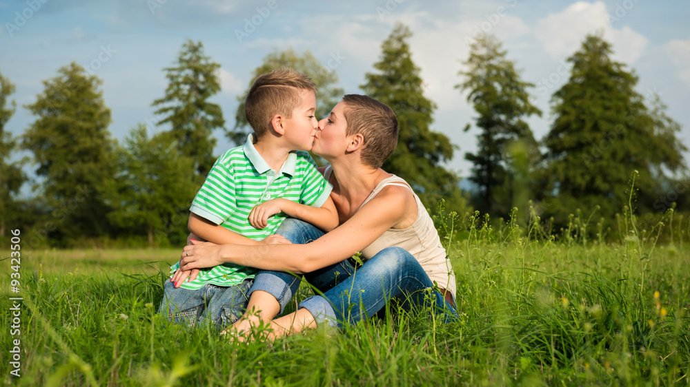 Mother and son kissing, posing for an outdoor portrait