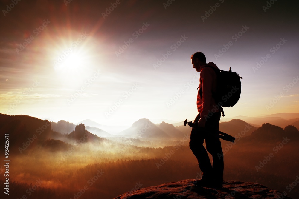 Silhouette of photographer overlooking a blanket of fog over valley to sun - obrazy, fototapety, plakaty 