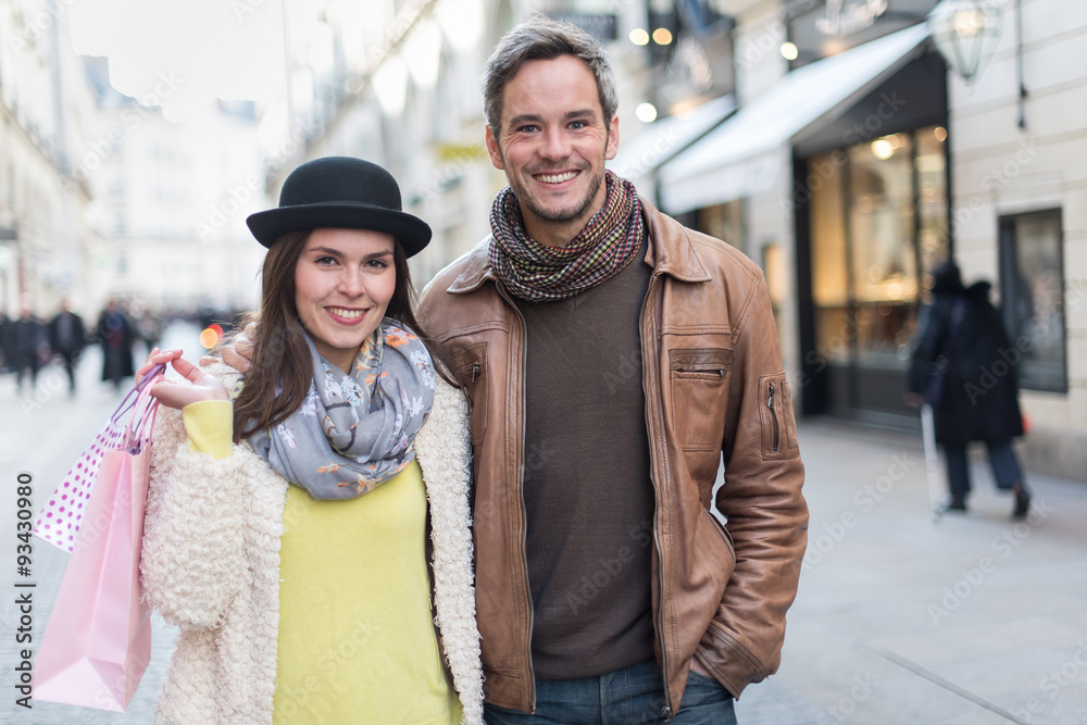A trendy couple is walking arm in arm in the city center