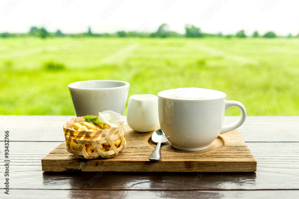 A cappuccino and some biscuits on the table and background lands A cappuccino and some biscuits on the table and background lands