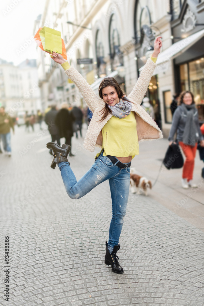 Obraz premium Smiling woman in her 30s with black boots and white coat jumping