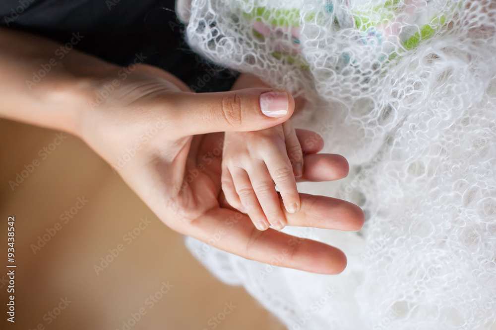 Newborn children's hand in mother hand. Mom and her Child. Happ Newborn children's hand in mother hand. Mom and her Child. Happ