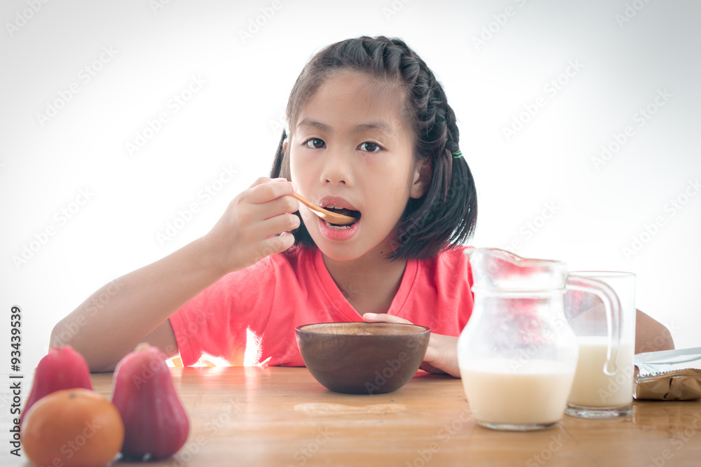 cute little Asian girl eating cereal with the milk on white back cute little Asian girl eating cereal with the milk on white back