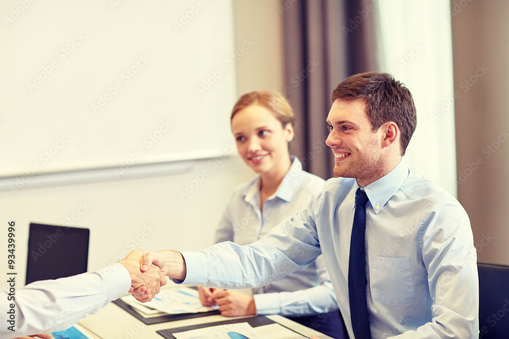 smiling business team shaking hands in office smiling business team shaking hands in office