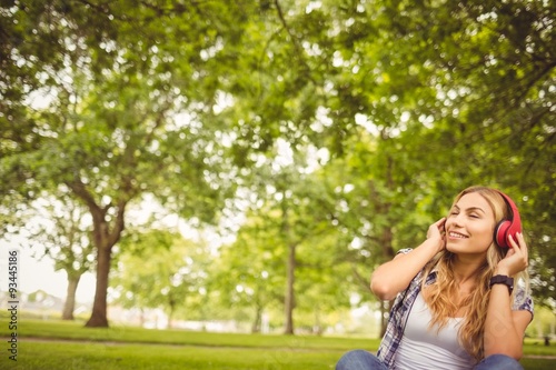 Happy woman enjoying music with eyes closed at park