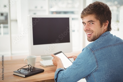 Happy businessman using digital tablet while sitting at desk  © WavebreakmediaMicro