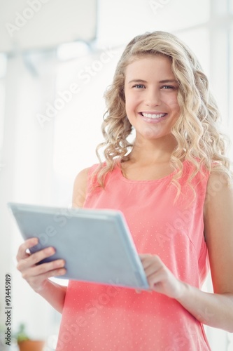 Portrait of smiling woman using digital tablet at office