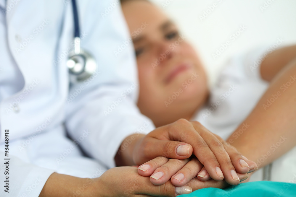 Friendly female doctor hands holding patient hand