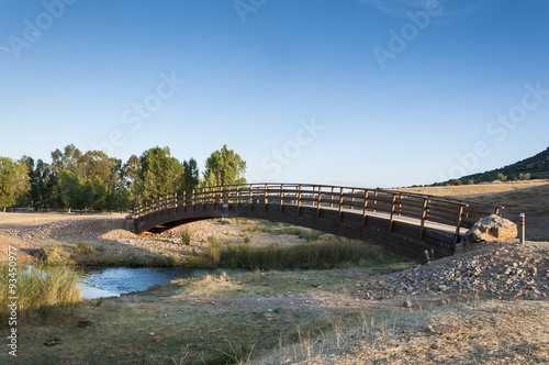 Small wooden bridge over the Bullaque River at its pass through Porzuna, La Mancha, Ciudad Real, Spain photo