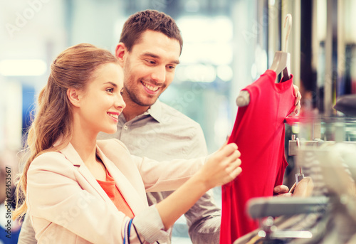 happy young couple choosing dress in mall