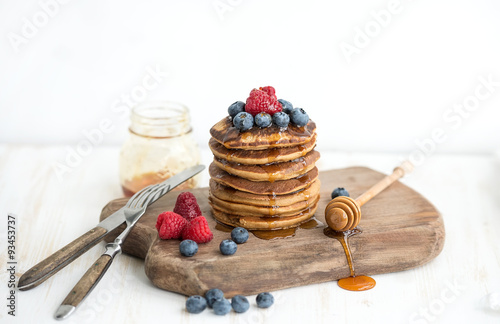 Buckwheat pancakes with fresh berries and honey on rustic wooden