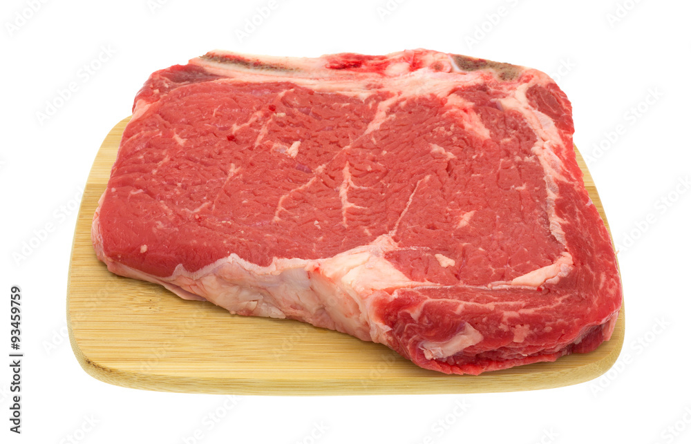 Bone in rib eye steak on wood cutting board Bone in rib eye steak on wood cutting board