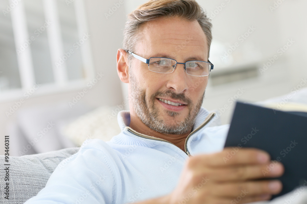 40-year-old man relaxing in sofa reading book 40-year-old man relaxing in sofa reading book