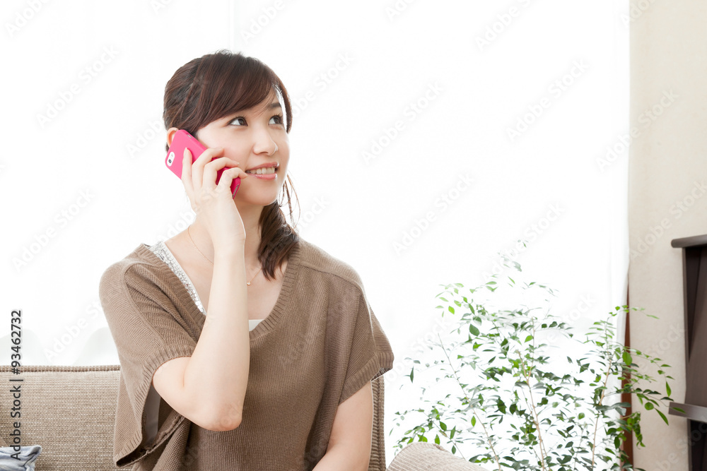 女性　携帯電話　話す　プライベート　家　ソファー